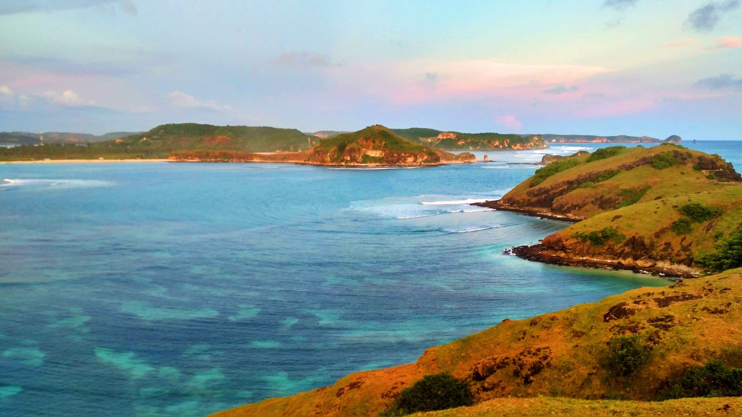 Turquoise water of Tanjung Aan bay and green headlands, seen from Bukit Merese hill in South Lombok